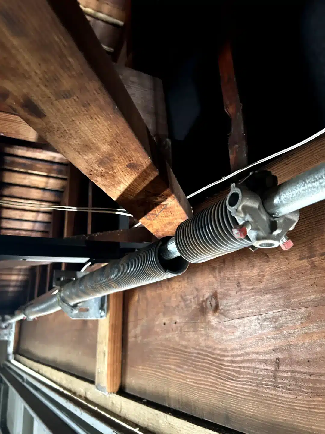 An up-close, interior view reveals a completely snapped torsion spring split along the shaft, demonstrating a critical failure that requires an immediate broken spring replacement.